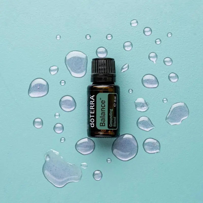 Mezcla dōTERRA Balance 15ml — frasco sobre fondo turquesa con gotas de agua, vista cenital