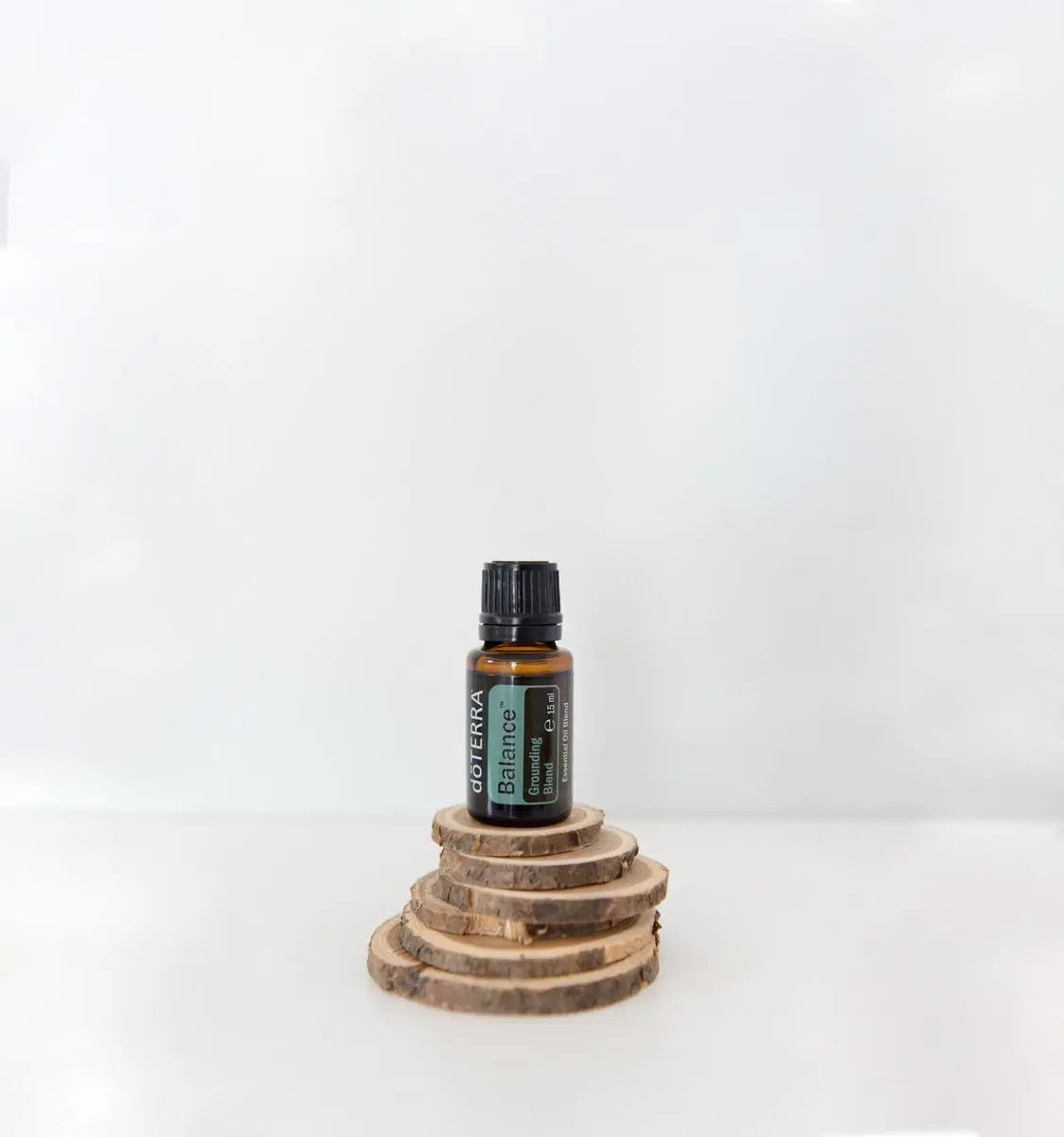 Mezcla dōTERRA Balance 15ml — frasco junto a rodajas de madera apiladas sobre fondo blanco
