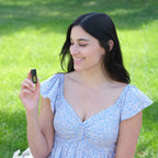 Mezcla dōTERRA Cheer 5ml — mujer con vestido azul floral sosteniendo el frasco en el jardín