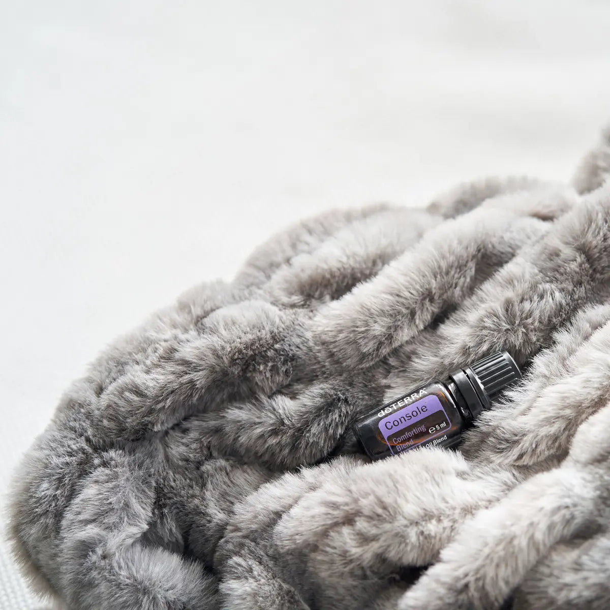 Mezcla dōTERRA Console 5ml — frasco sobre manta peluda gris de textura suave y acogedora