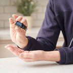 Mezcla dōTERRA Deep Blue 5ml — persona con chándal azul aplicando una gota en la palma en la cocina