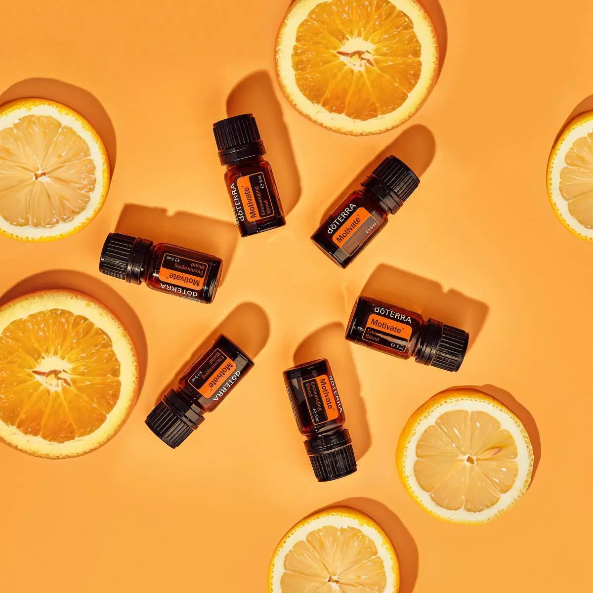 Mezcla dōTERRA Motivate 5ml — cinco frascos con rodajas de naranja sobre fondo naranja, vista cenital