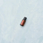 Mezcla dōTERRA On Guard 15ml — frasco tumbado sobre mármol azul claro, vista cenital minimalista