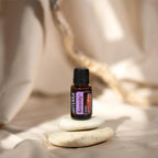 Mezcla dōTERRA Serenity 15ml — frasco junto a piedras zen apiladas con luz cálida y fondo beige
