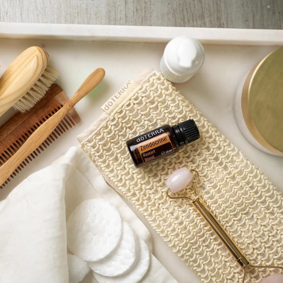 Mezcla dōTERRA Zendocrine 15ml — frasco en rutina de bienestar con esponja, rodillo de cuarzo y peine sobre mármol
