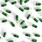 Macro de capsulas bicolor verde y transparente de PB Restore doTERRA dispersas sobre fondo blanco mostrando el contenido del suplemento probiotico