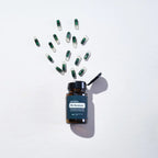 PB Restore doTERRA visto desde arriba con frasco abierto y capsulas bicolor verde y transparente dispersas en forma de explosion sobre fondo blanco