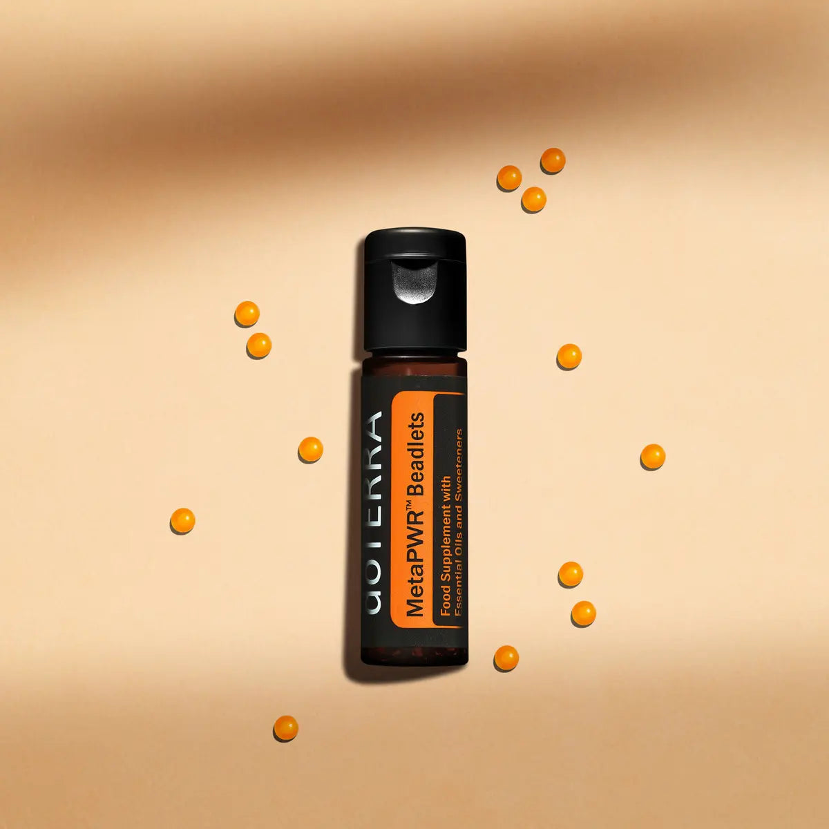 Perlas MetaPWR dōTERRA — frasco vertical con bolitas naranjas dispersas sobre fondo tostado, vista cenital