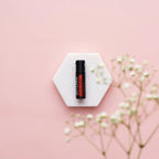 Perlas On Guard dōTERRA — frasco en posavasos hexagonal de mármol con gypsophila, flores blancas y rosas
