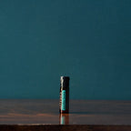 Perlas Supermint dōTERRA — frasco sobre mesa de madera oscura con fondo verde azulado en estudio