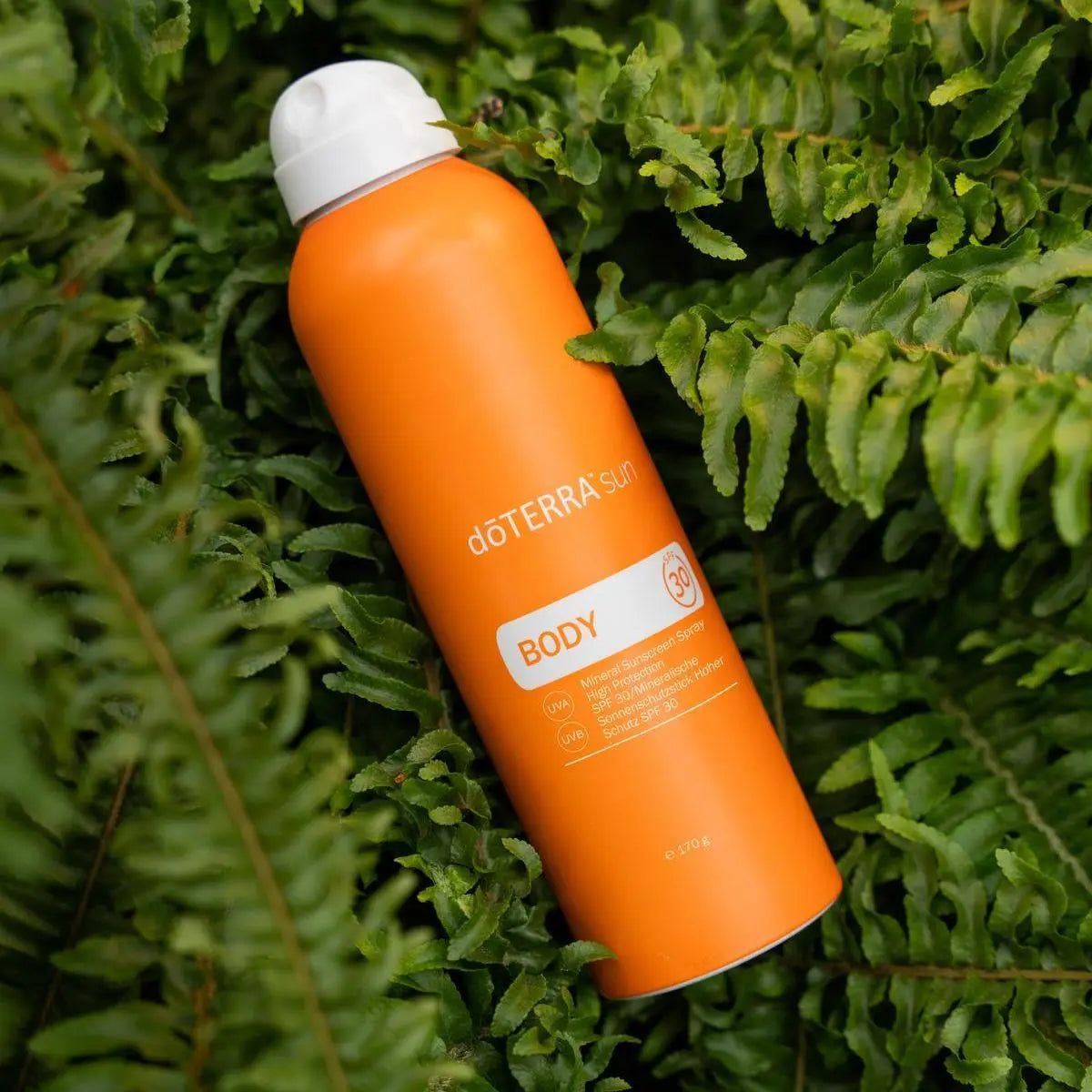Protector solar Sun Body Spray dōTERRA SPF 30 170g — frasco entre helechos verdes vista cenital