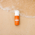 Protector solar Sun Face dōTERRA SPF 30 — frasco en arena húmeda con espuma de ola