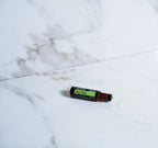 Árbol de Té Touch dōTERRA 10ml tumbado sobre mármol blanco y dorado