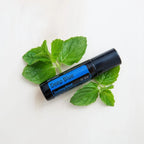 Roll-on dōTERRA Deep Blue 10ml — sobre hojas de menta fresca en superficie blanca, vista cenital