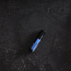 Roll-on dōTERRA Deep Blue 10ml — tumbado sobre granito negro texturizado, vista cenital