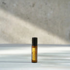 Roll-on Helichrysum Touch dōTERRA 10ml — dos frascos con flores amarillas y efecto bokeh