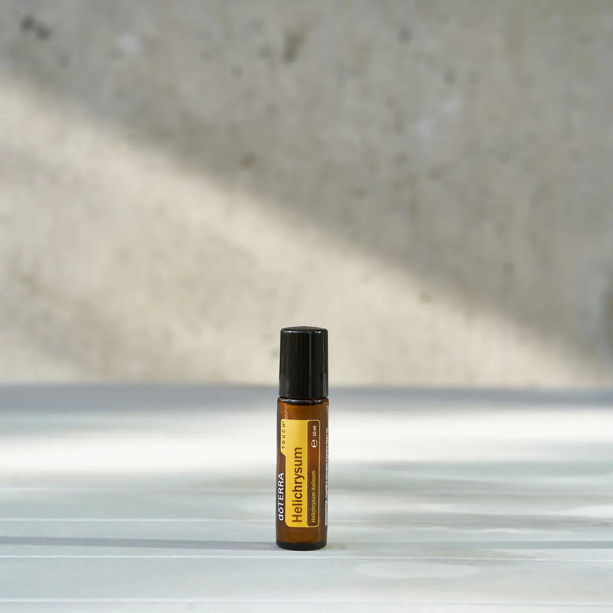 Roll-on Helichrysum Touch dōTERRA 10ml — dos frascos con flores amarillas y efecto bokeh