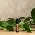 Roll-on Helichrysum Touch dōTERRA 10ml — mano sosteniendo el frasco en escena botánica
