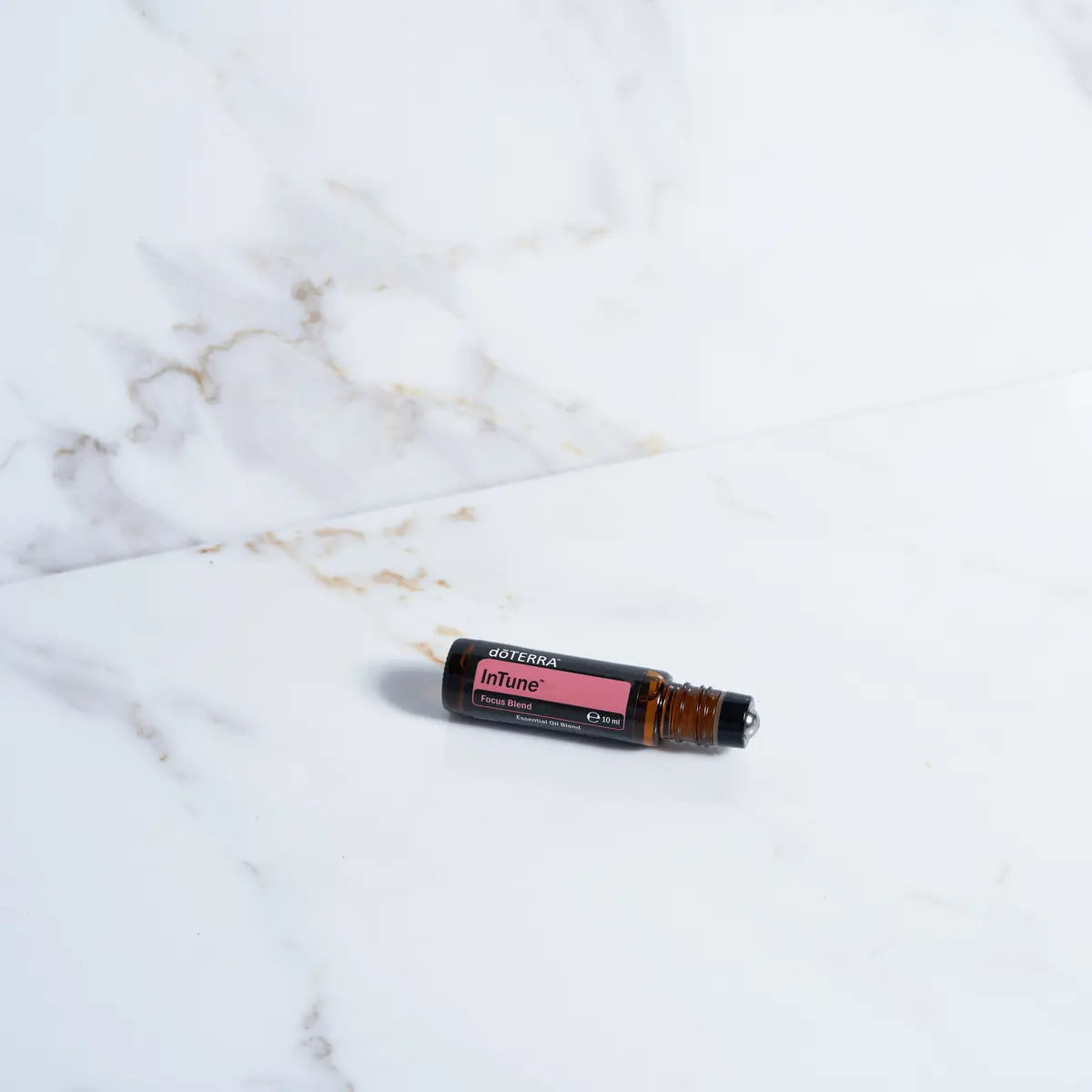 Roll-on InTune Touch dōTERRA 10ml — frasco en estudio con fondo beige