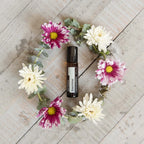 Jazmín Touch dōTERRA 10ml en corona de crisantemos blancos y malvas sobre madera vista cenital
