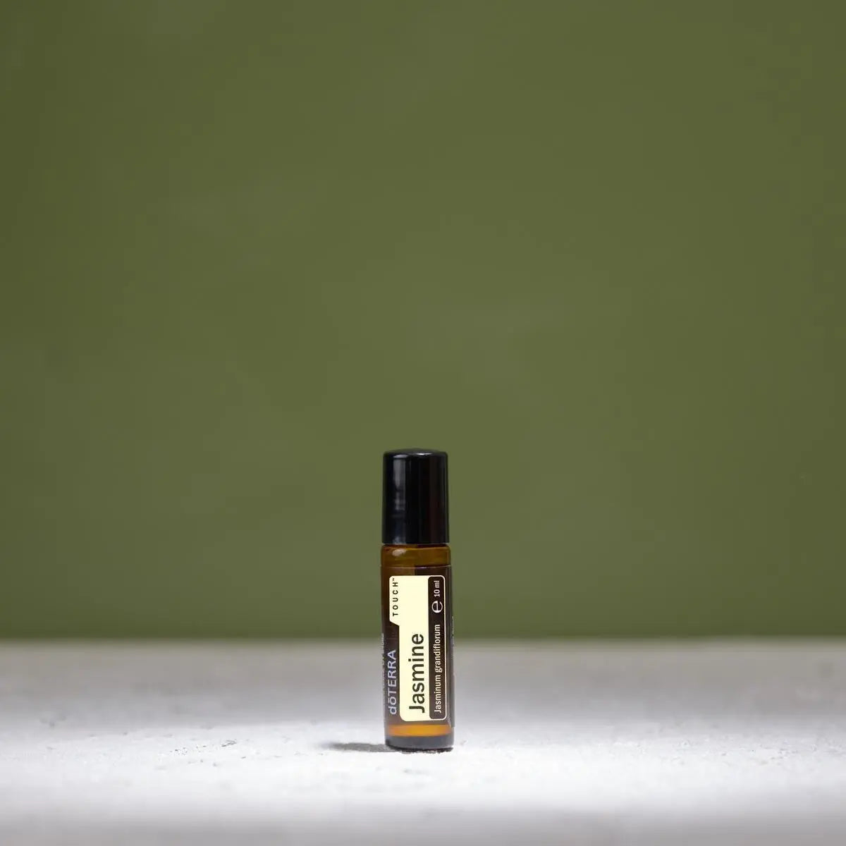 Jazmín Touch dōTERRA 10ml solo sobre fondo verde oliva minimalista