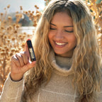 Mujer rubia rizada sonriendo con Jazmín Touch dōTERRA 10ml en campo dorado exterior