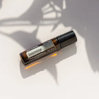Jazmín Touch dōTERRA 10ml sobre superficie blanca con sombras de hojas naturales
