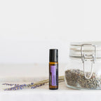 Lavanda Touch dōTERRA roll-on 10ml junto a lavanda seca en tarro de cristal con ramita sobre fondo blanco