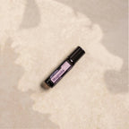 Magnolia Touch dōTERRA 10ml tumbado sobre piedra beige con sombras de hojas