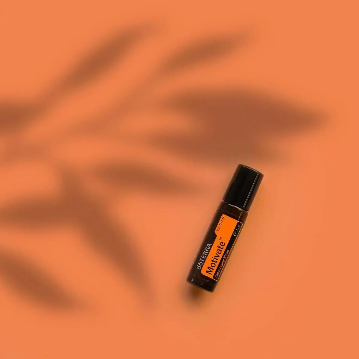 Roll-on Motivate Touch dōTERRA 10ml — frasco sobre fondo naranja con sombras de palmera