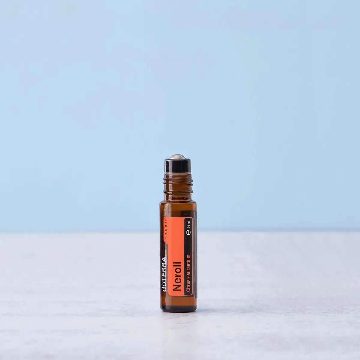 Neroli Touch dōTERRA 10ml frasco solo sobre mármol blanco con fondo azul claro