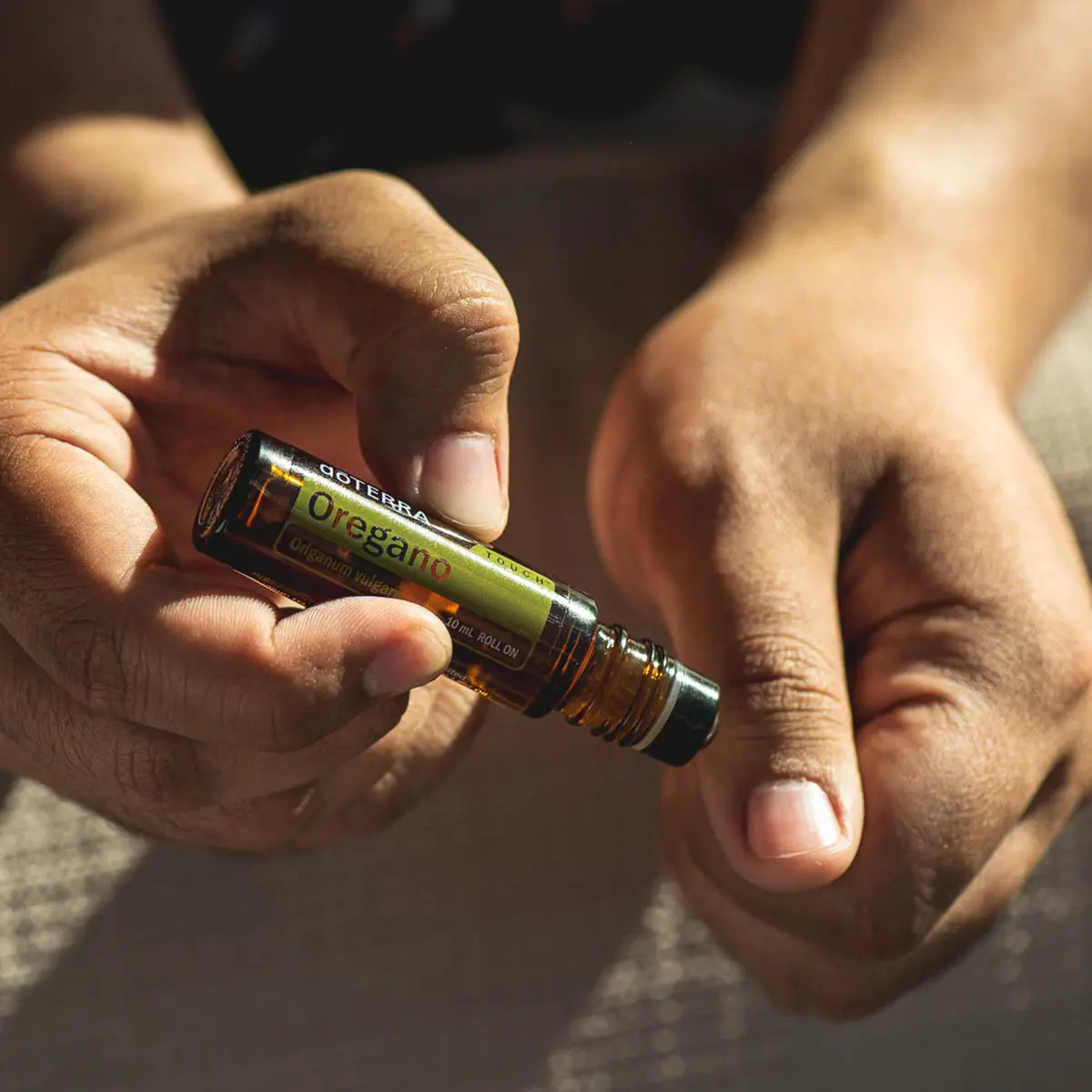 Manos aplicando Orégano Touch dōTERRA 10ml sobre la piel con luz solar cálida