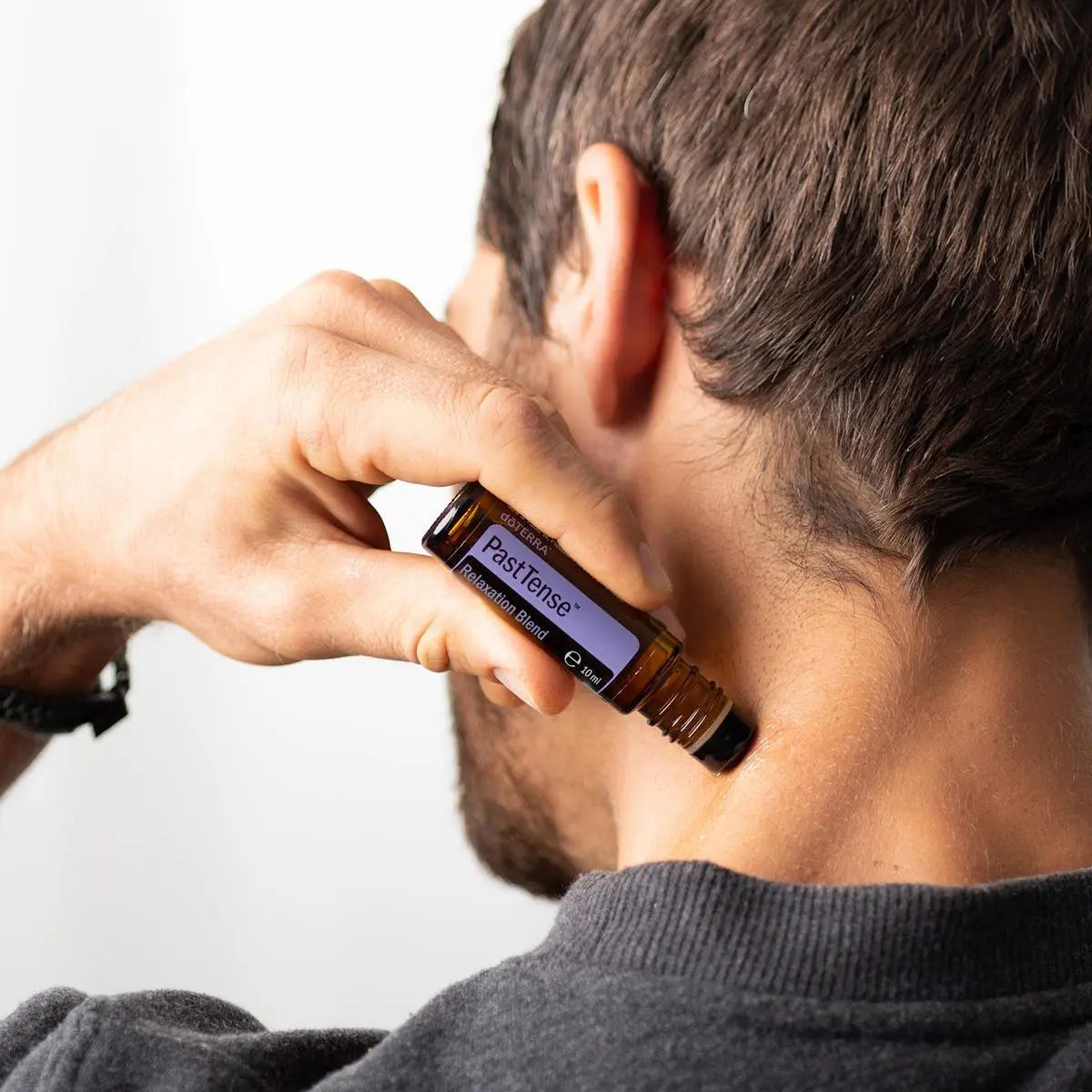 Roll-on PastTense dōTERRA 10ml — hombre aplicando el roll-on en la nuca, primer plano