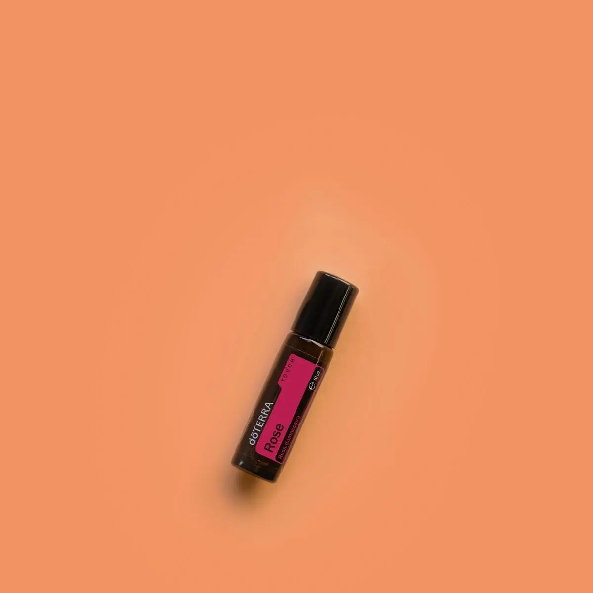 Rosa Touch dōTERRA 10ml frasco solo sobre fondo naranja coral minimalista