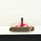 Rosa Touch dōTERRA 10ml sobre tabla de madera rústica con pétalos de rosa y azulejo de baño