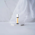 Roll-on Thinker dōTERRA 10ml — frasco sobre pedestal blanco con tela drapeada y mármol