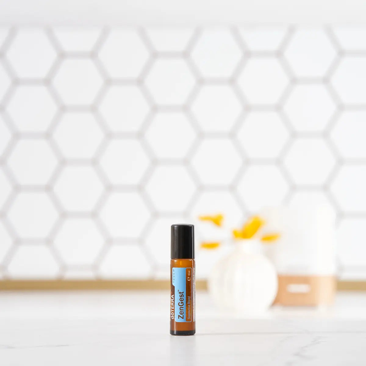 Roll-on ZenGest Touch dōTERRA 10ml — frasco sobre encimera con azulejos hexagonales y vela