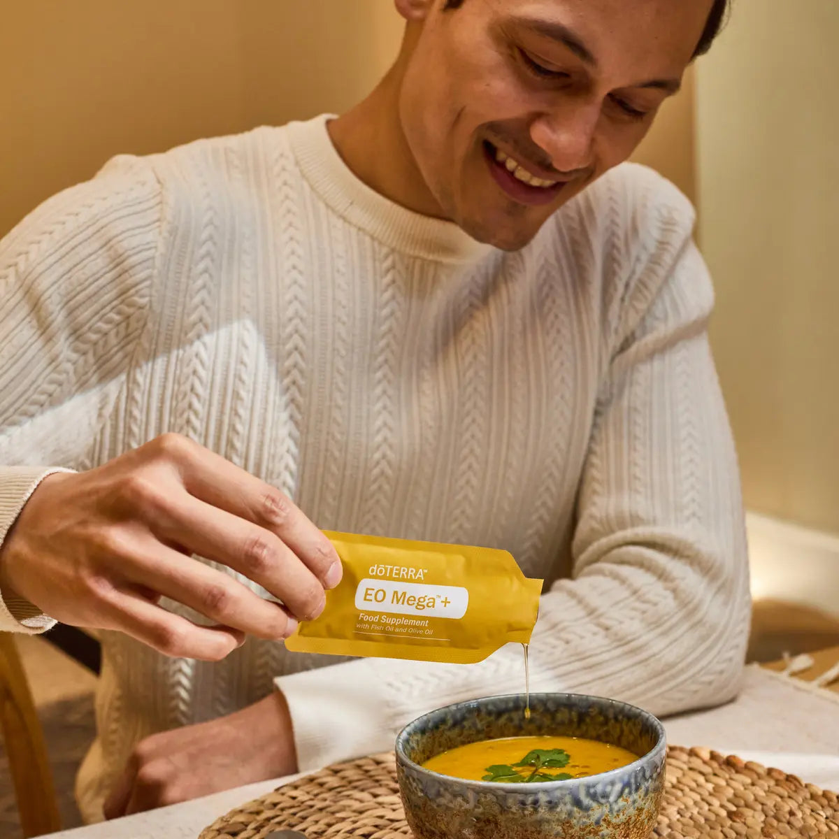 Hombre sonriente echando suplemento EO Mega+ dōTERRA en sopa caliente