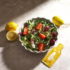 Sobre de EO Mega+ dōTERRA junto a ensalada verde, tomate y limón sobre mármol visto desde arriba
