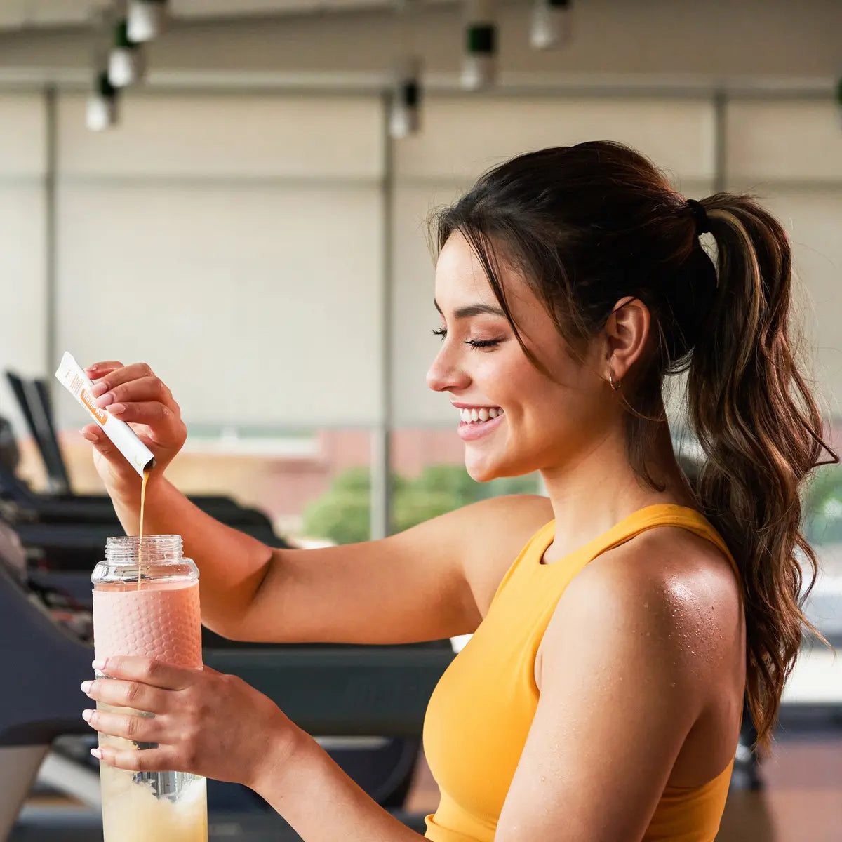 MetaPWR™ Advantage dōTERRA — mujer en el gimnasio con botella naranja
