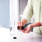 Meta-PWR™ Assist dōTERRA — mujer sonriente con el frasco en la cocina