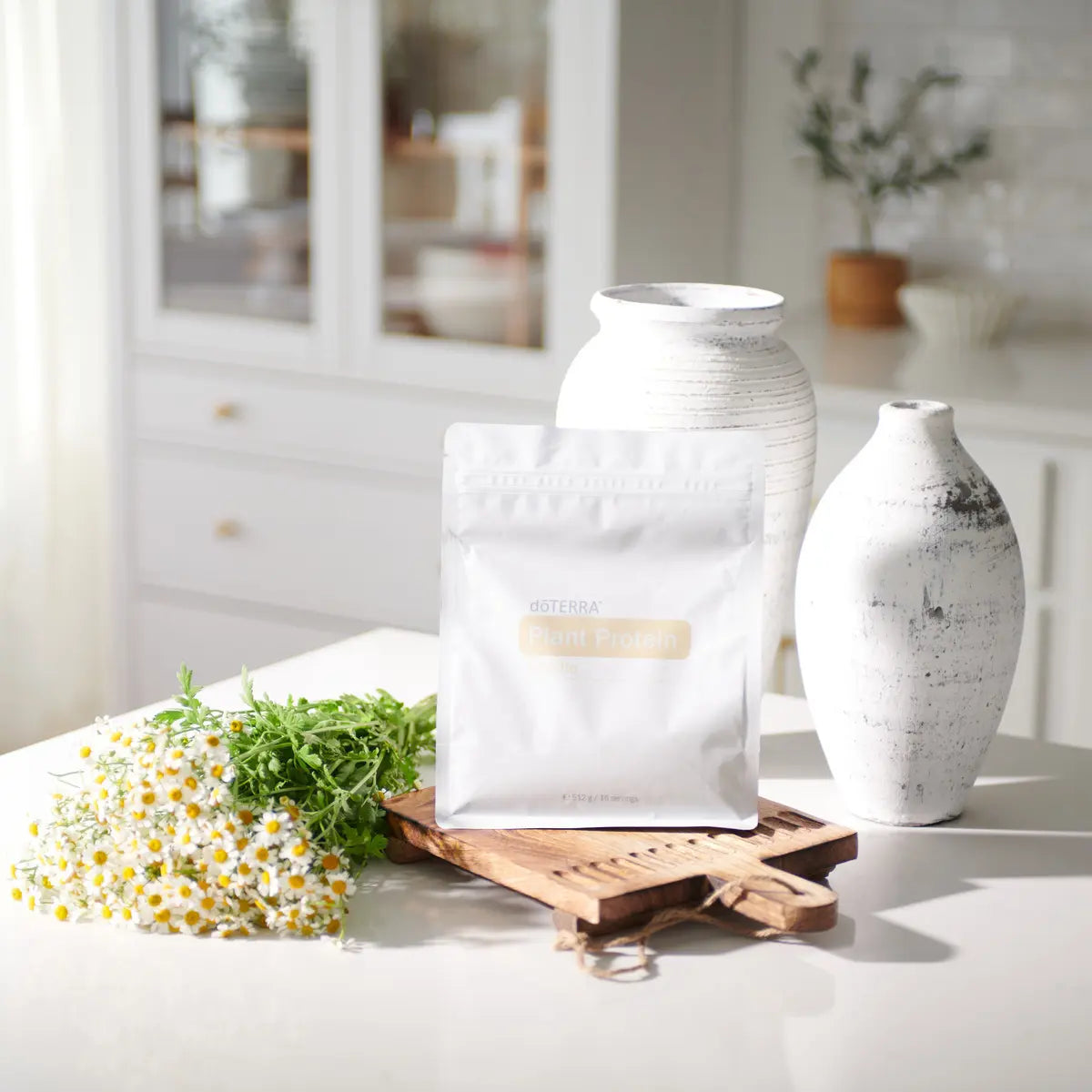 Bolsa de proteína vegetal de vainilla dōTERRA 512g decorada con jarrones blancos y manzanilla