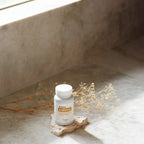 Frasco blanco de Complejo Zendocrine dōTERRA 60ct sobre piedra con ramas secas