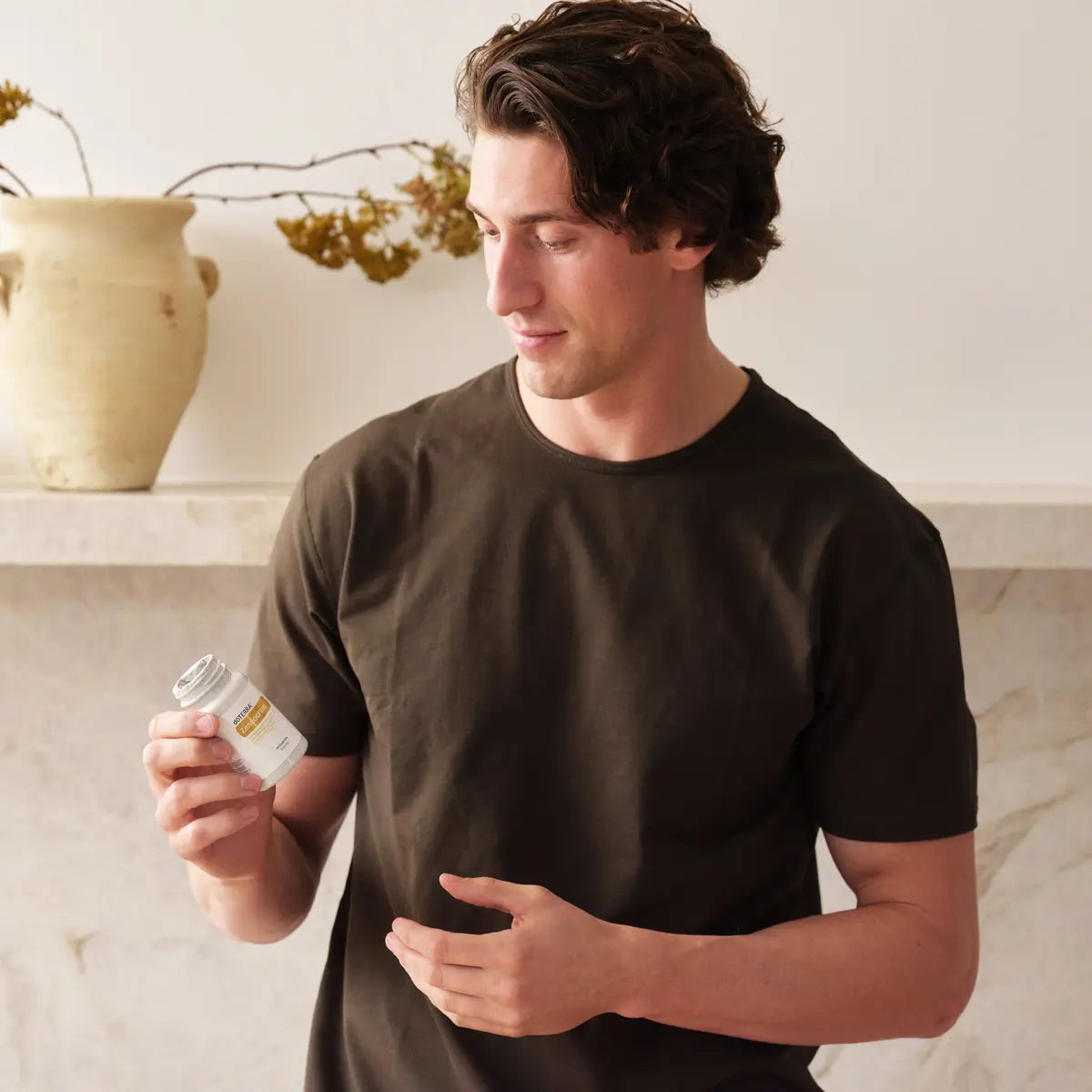 Hombre moreno sosteniendo frasco de Complejo Zendocrine dōTERRA 60ct