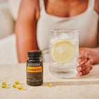 Frasco negro de Zendocrine Softgels dōTERRA con softgels, vaso y limón en la encimera