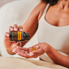 Manos con frasco inclinado de Zendocrine Softgels dōTERRA y softgel en la palma